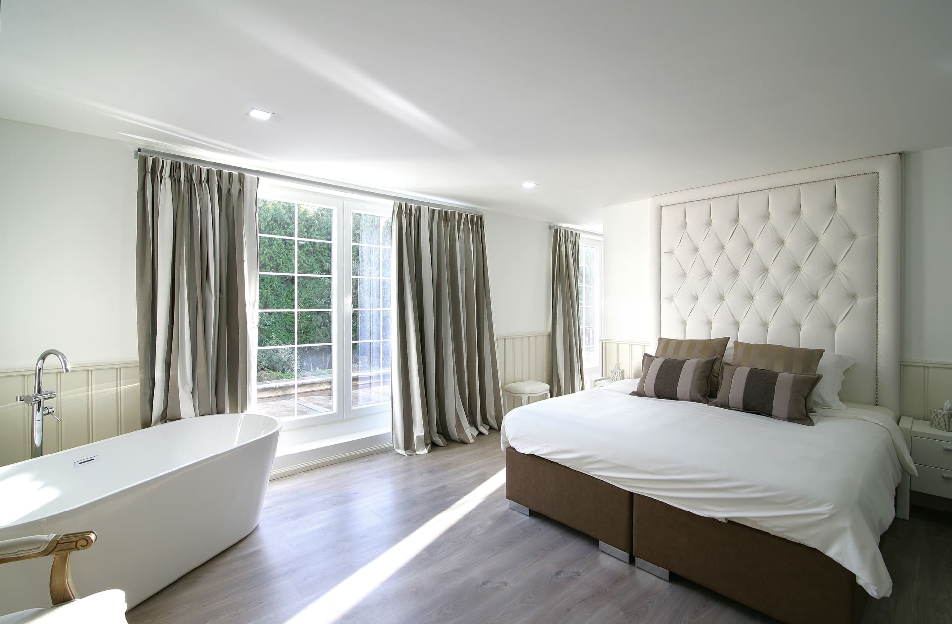 Schlafzimmer mit kapitoniertem Kopfteil und einem Durchgang zum Bad