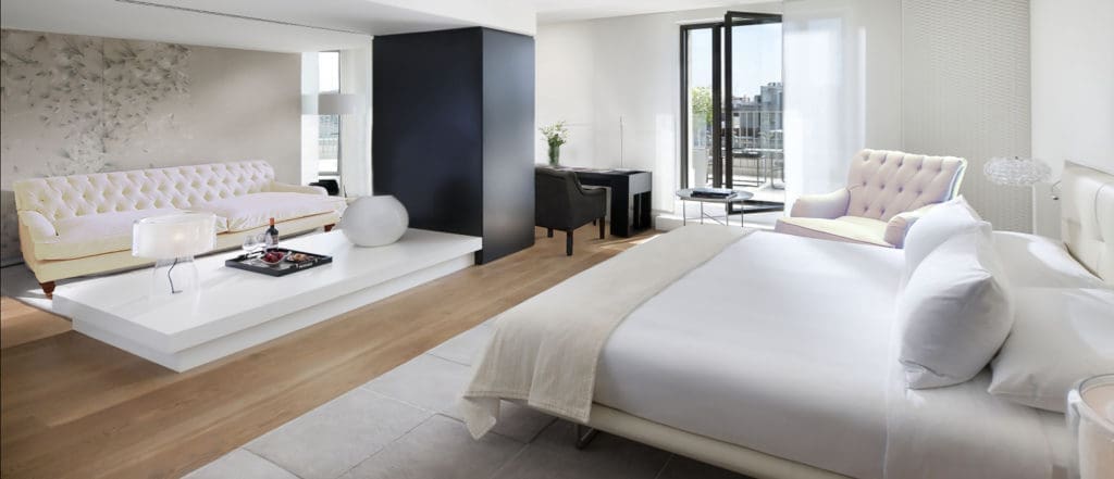 Hotelkamer met een bed in wit en een zithoek bij het raam