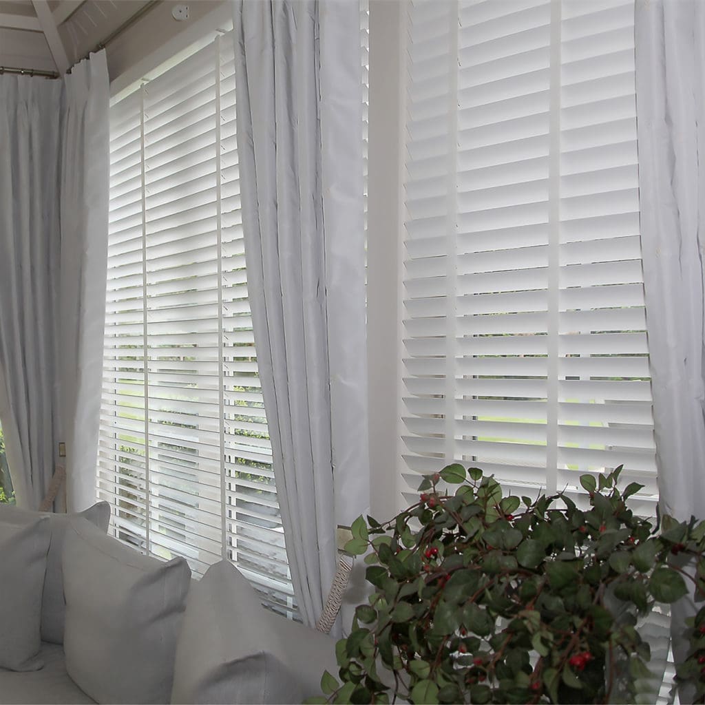 Shutters in wit hout voor het raam, met gordijnen ernaast