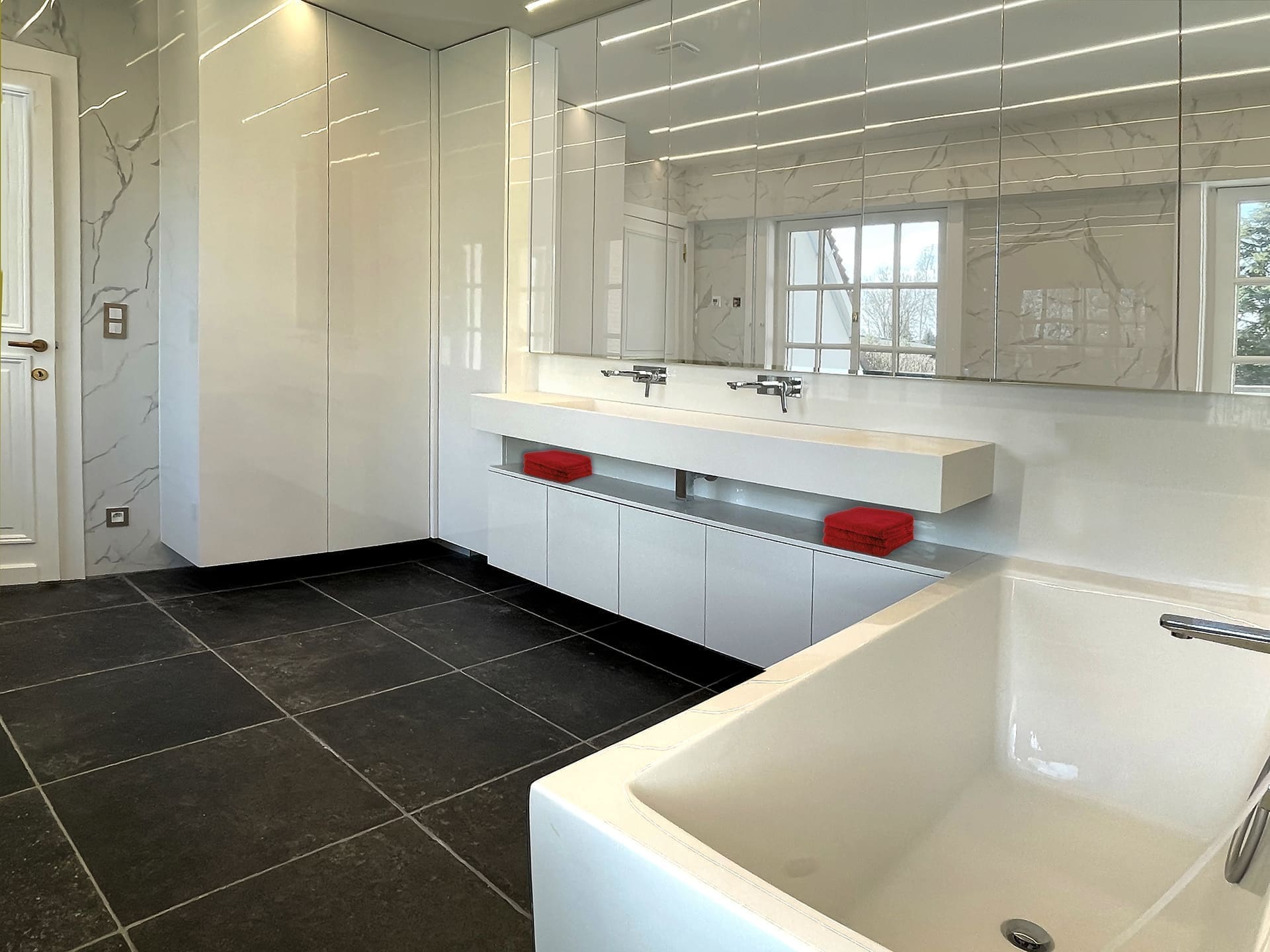 Wandkranen in chroom boven een lange wastafel in wit marmer