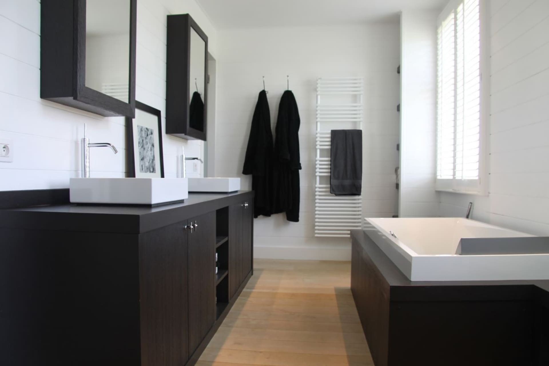 Badkamer met een donker gelakt meubel, opzetkommen en een ingebouwd bad