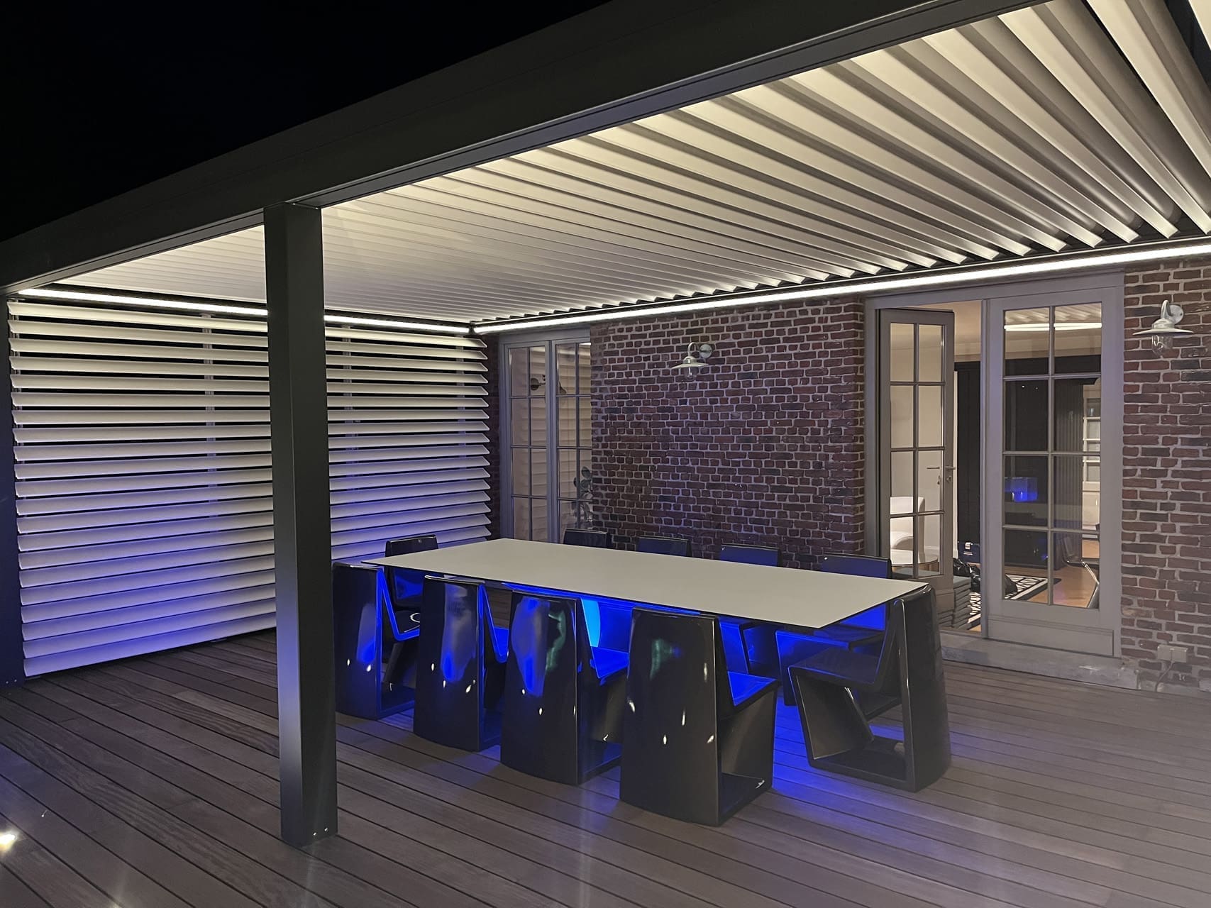 Außentisch mit blauem Licht unter der Platte, unter einer Pergola mit beleuchteten Lamellen