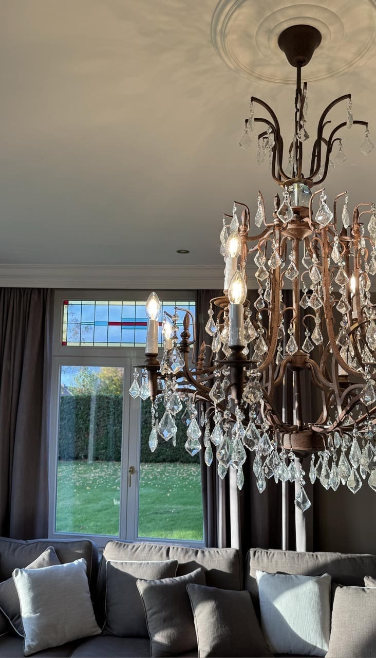 Kronleuchter aus patiniertem Metall mit Kristalltropfen vor dem Bleiglas, Villa in Hamont-Achel