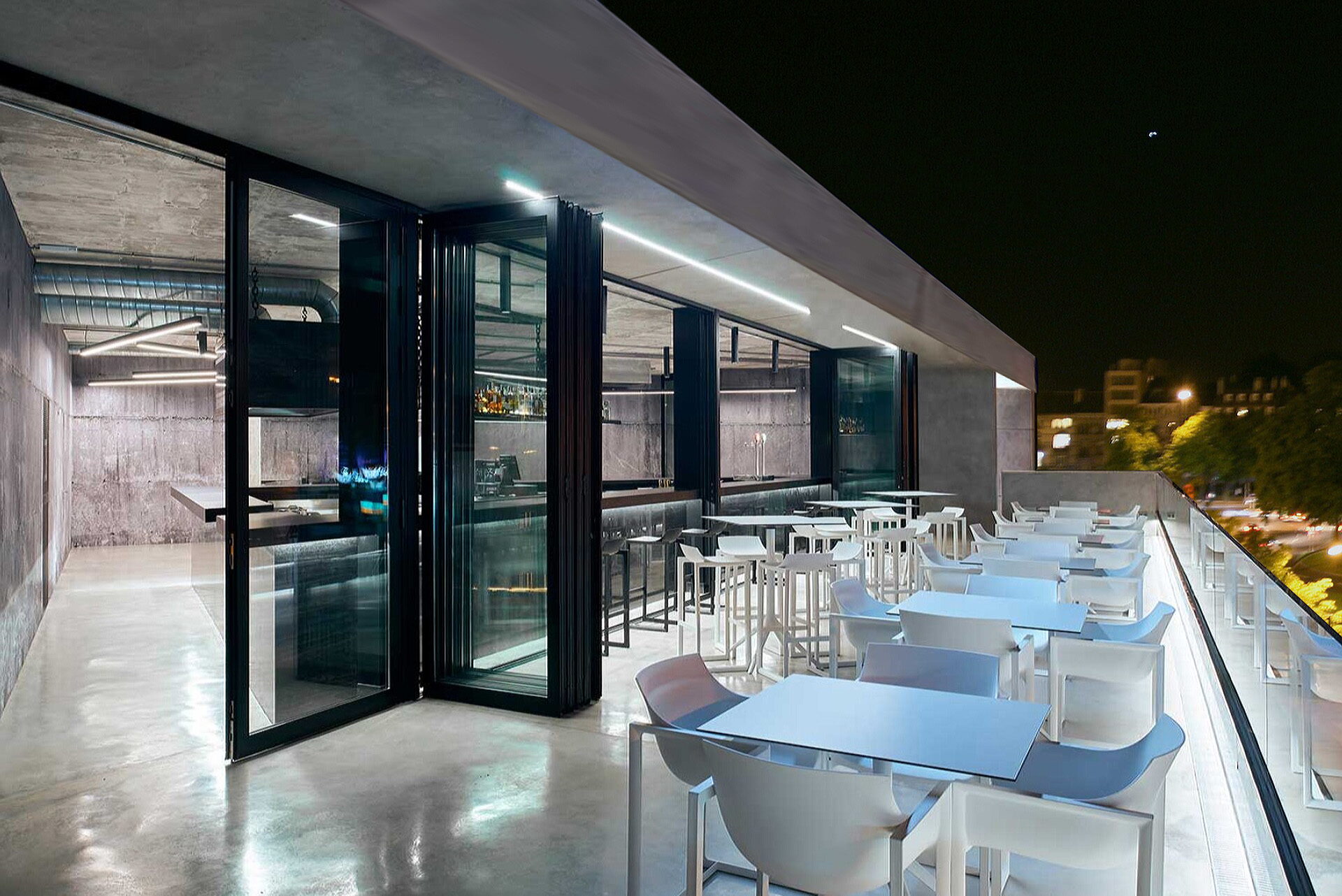 Überdachte Terrasse mit Faltfenstern und weißen Tischen entlang des Randes