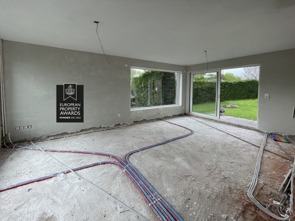 Ruwbouw tijdens een renovatie, met de leidingen in de vloer klaar voor de afwerking