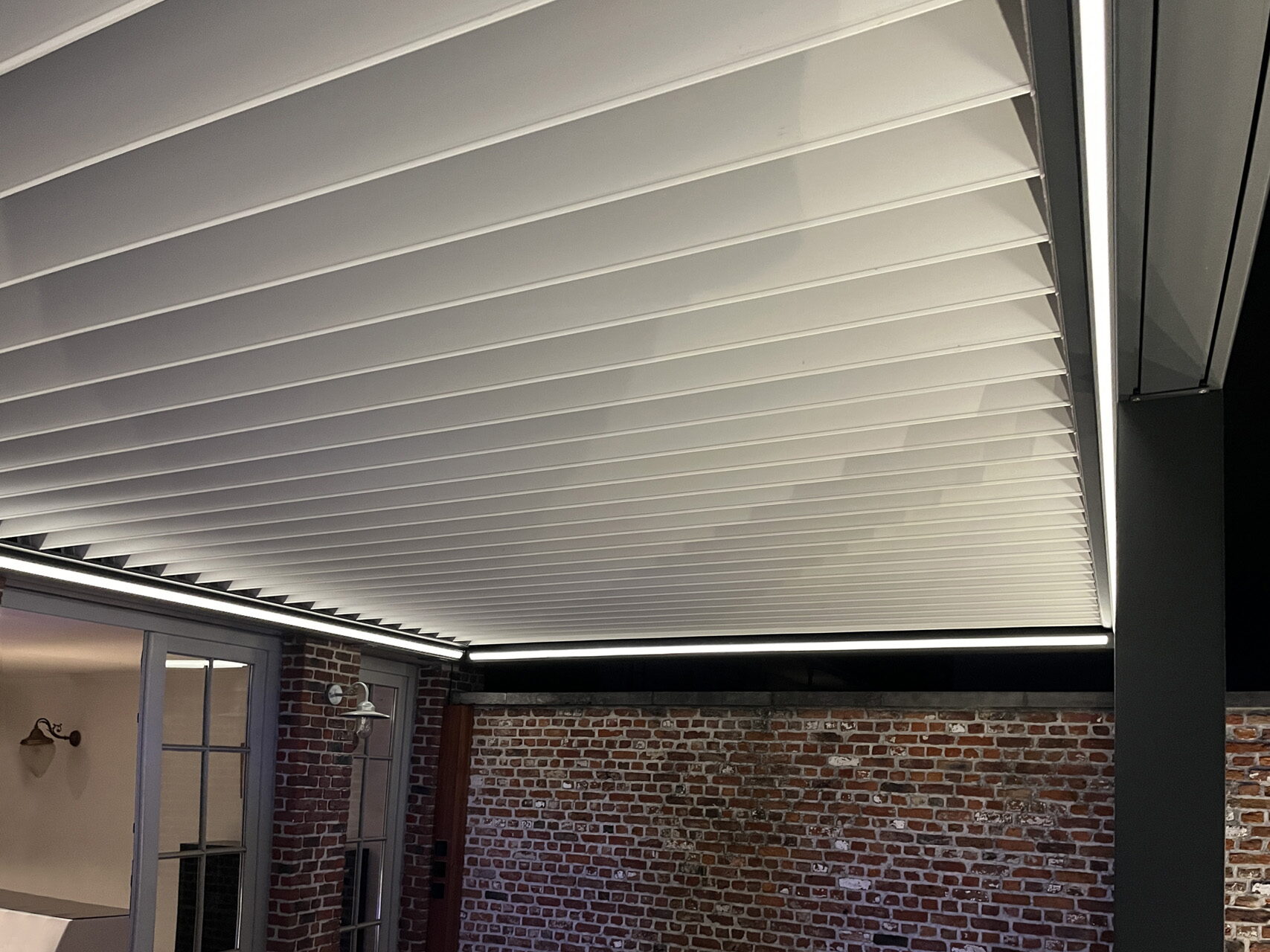 Aluminium-Pergola mit geschlossenen Lamellen und einer durchgehenden Lichtlinie über einer Terrasse