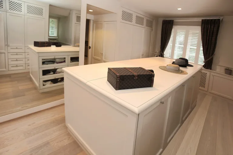 Een dressing met open legvakken, een eiland in het midden en verlichting in de planken.