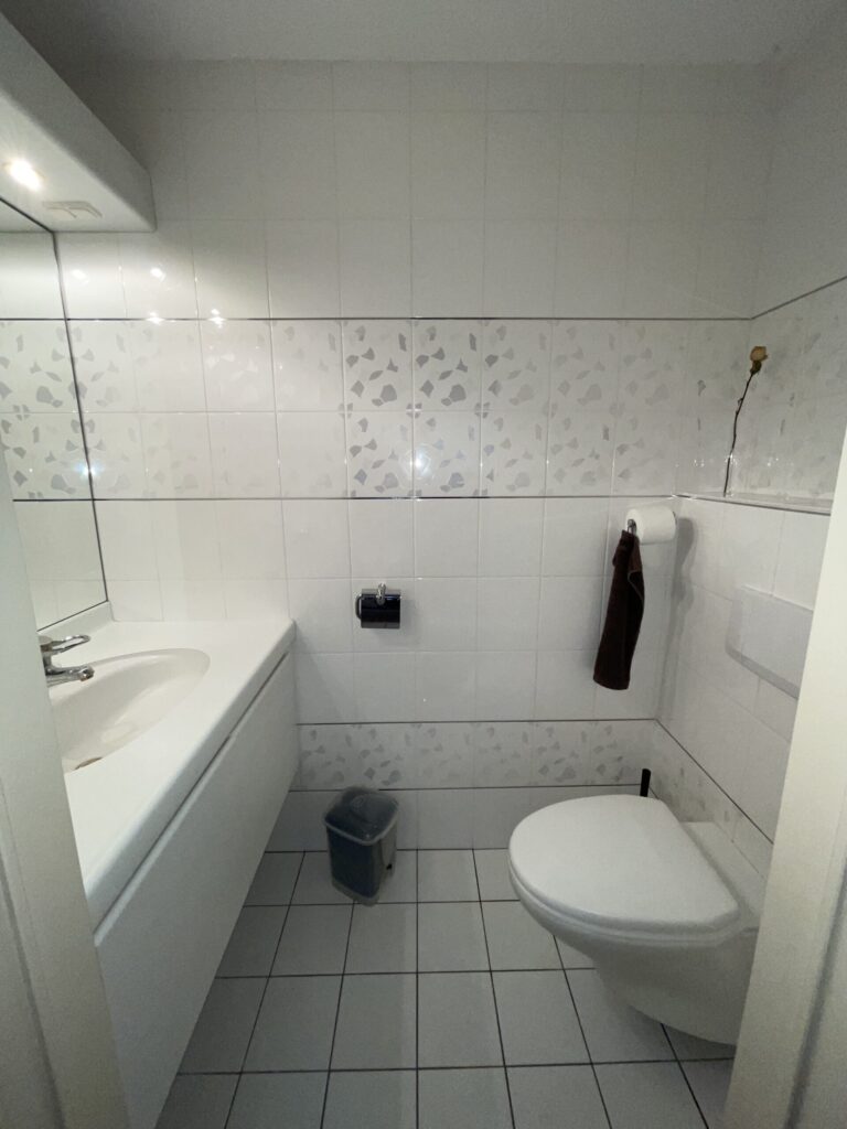 De oude badkamer met witte tegels, ligbad en een smalle indeling