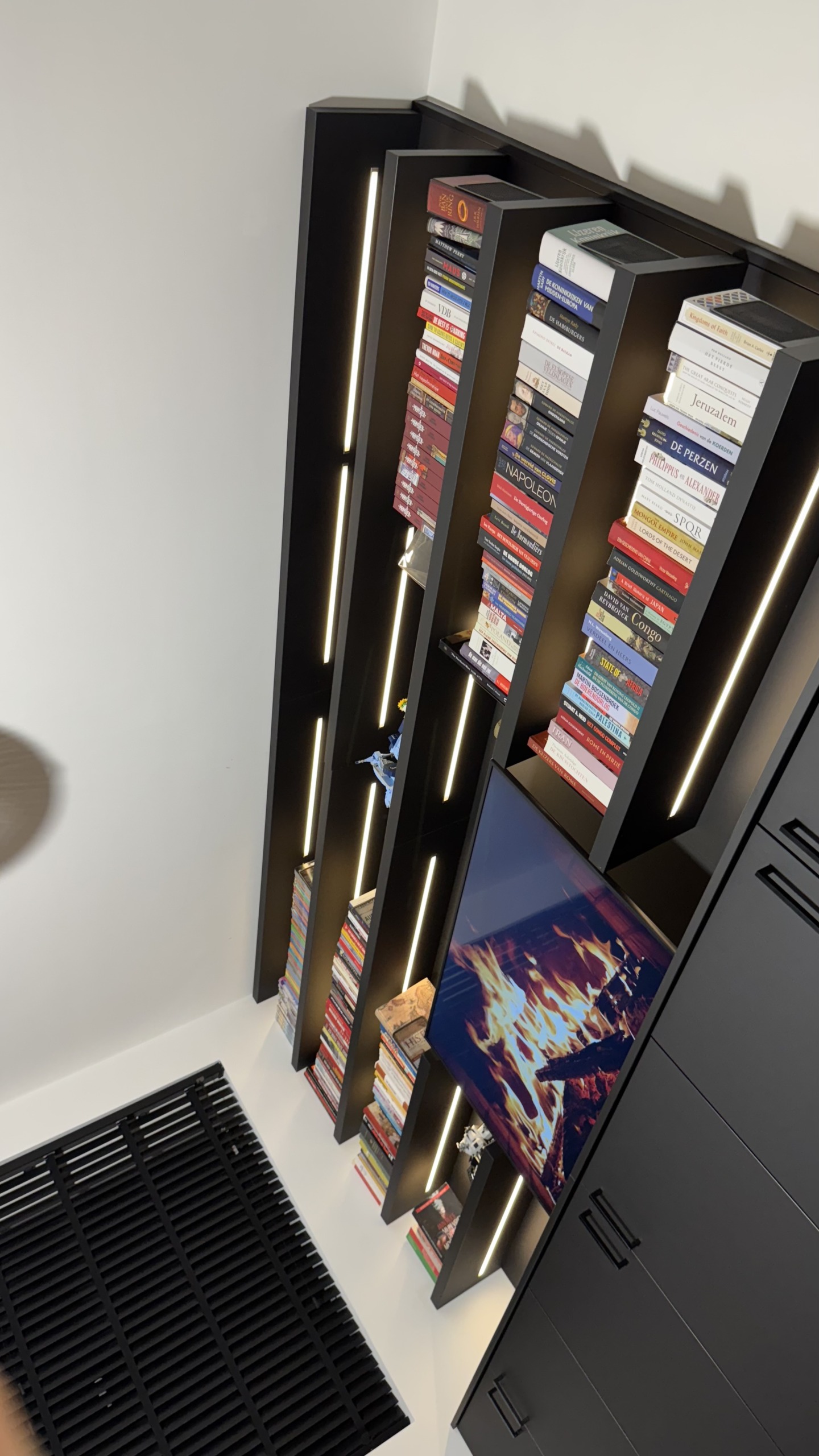 De boekenplanken van opzij, met de verlichting die de rug van de boeken aanlicht