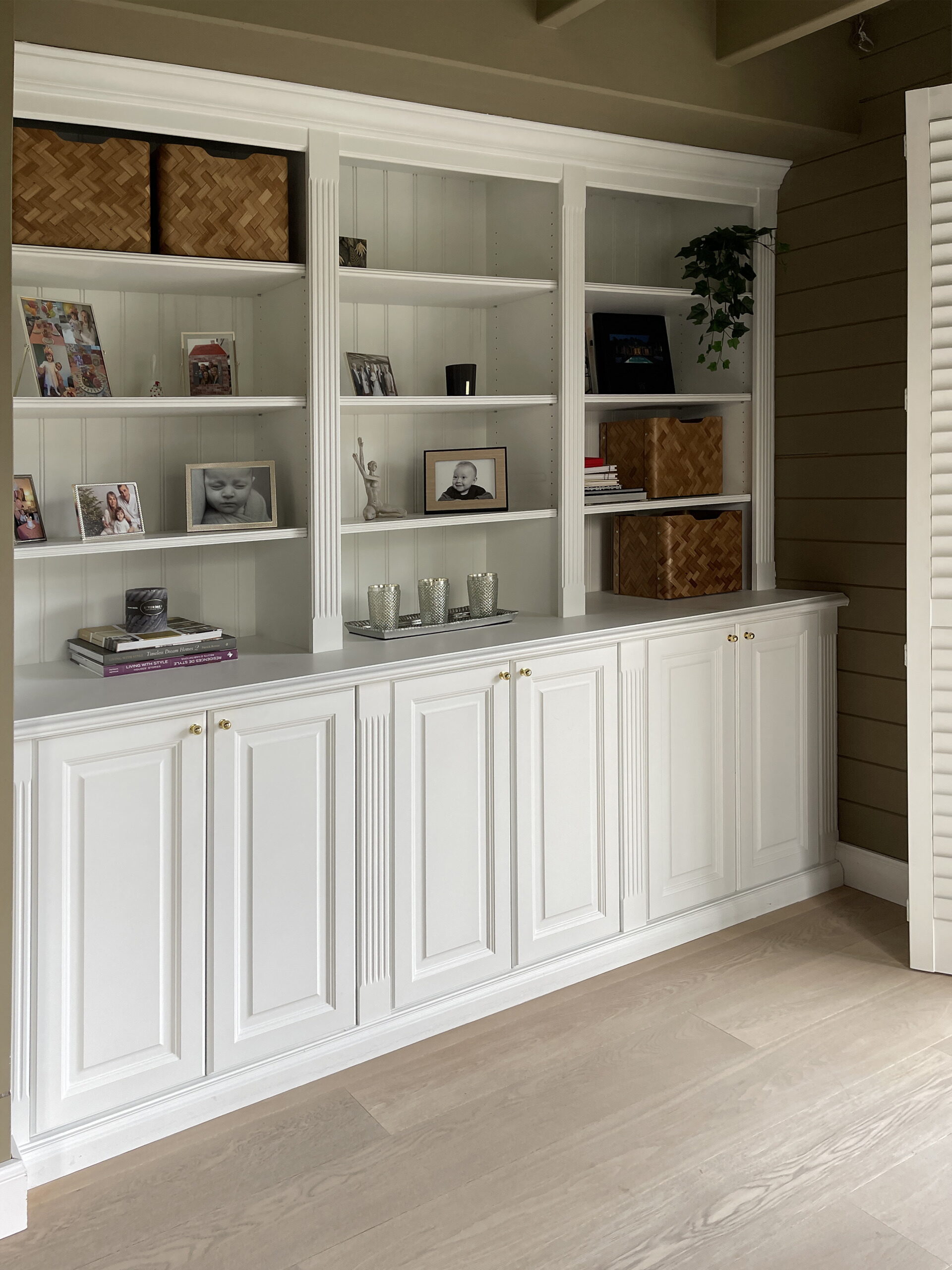 Witte bergkast op maat met open vakken en messing knoppen