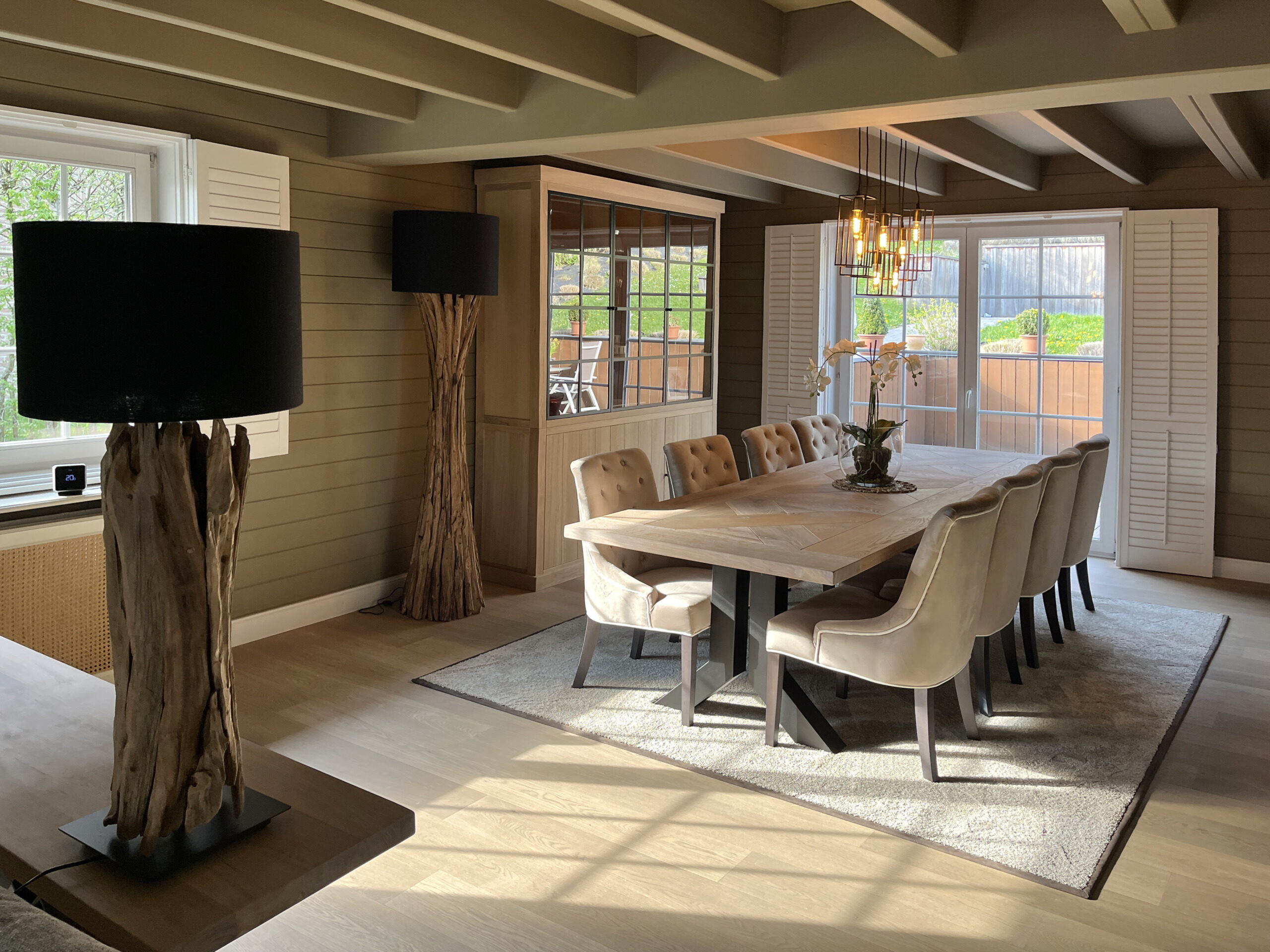 Eetkamer met eiken tafel, gecapitonneerde stoelen en drijfhoutlampen