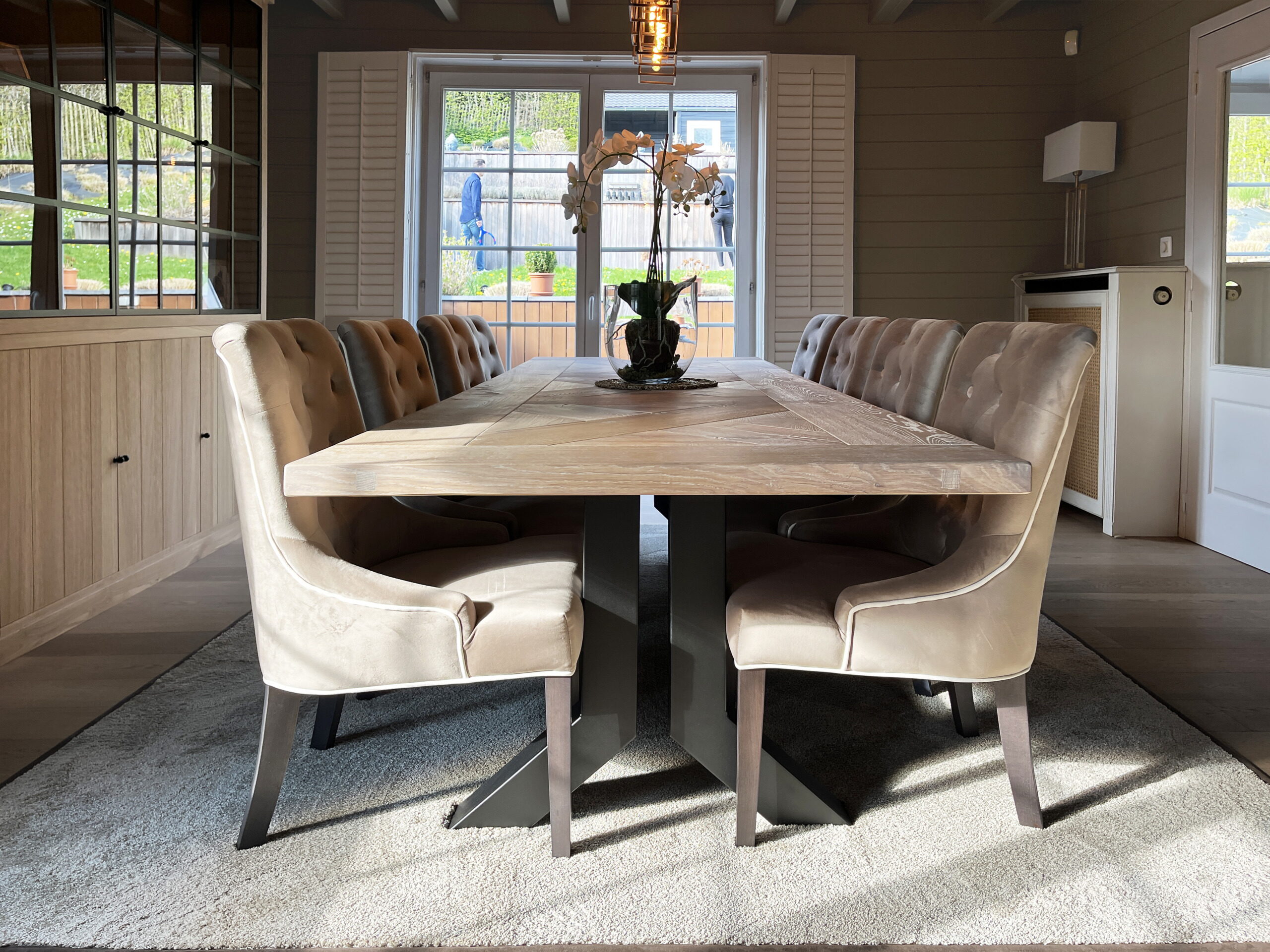Eiken eettafel met gecapitonneerde velours stoelen en terrasdeuren