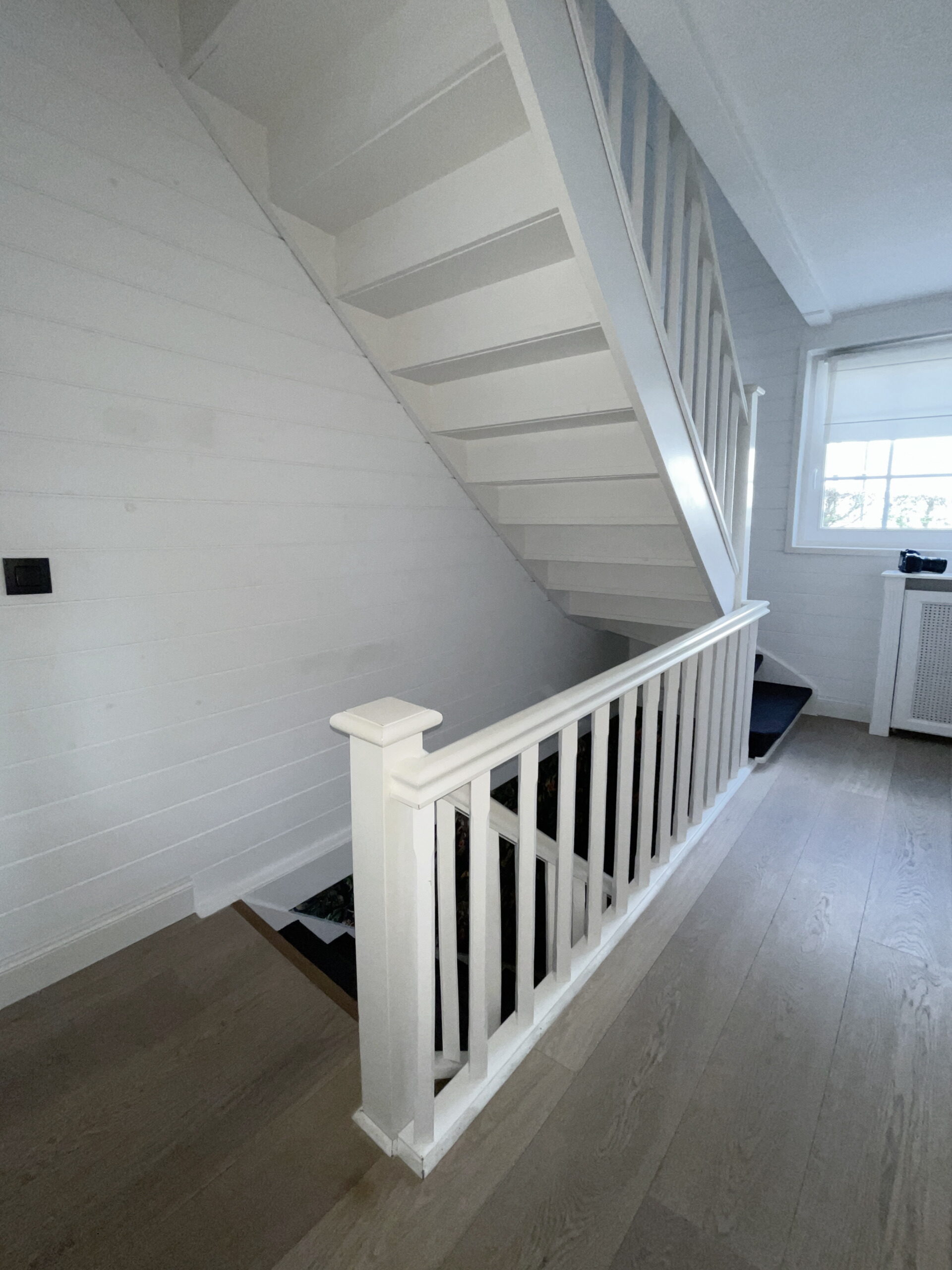 Witte trap met houten vloer op de bovenverdieping