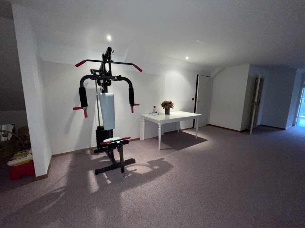 De open zolderruimte voor de werken, met fitnesstoestel en tapijt, waar later de dressing kwam