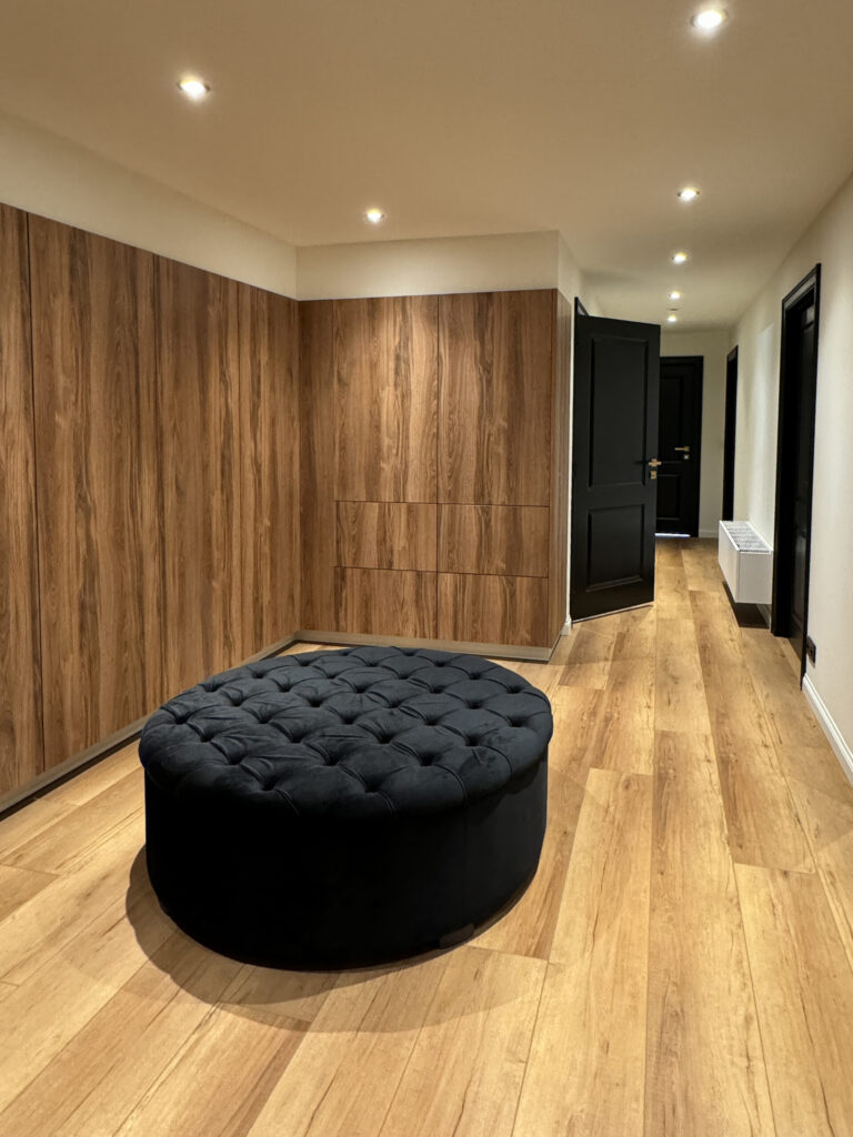 Vloer tot plafond kastenwand in notenhout met greeploze deuren in een dressing in Kapellen