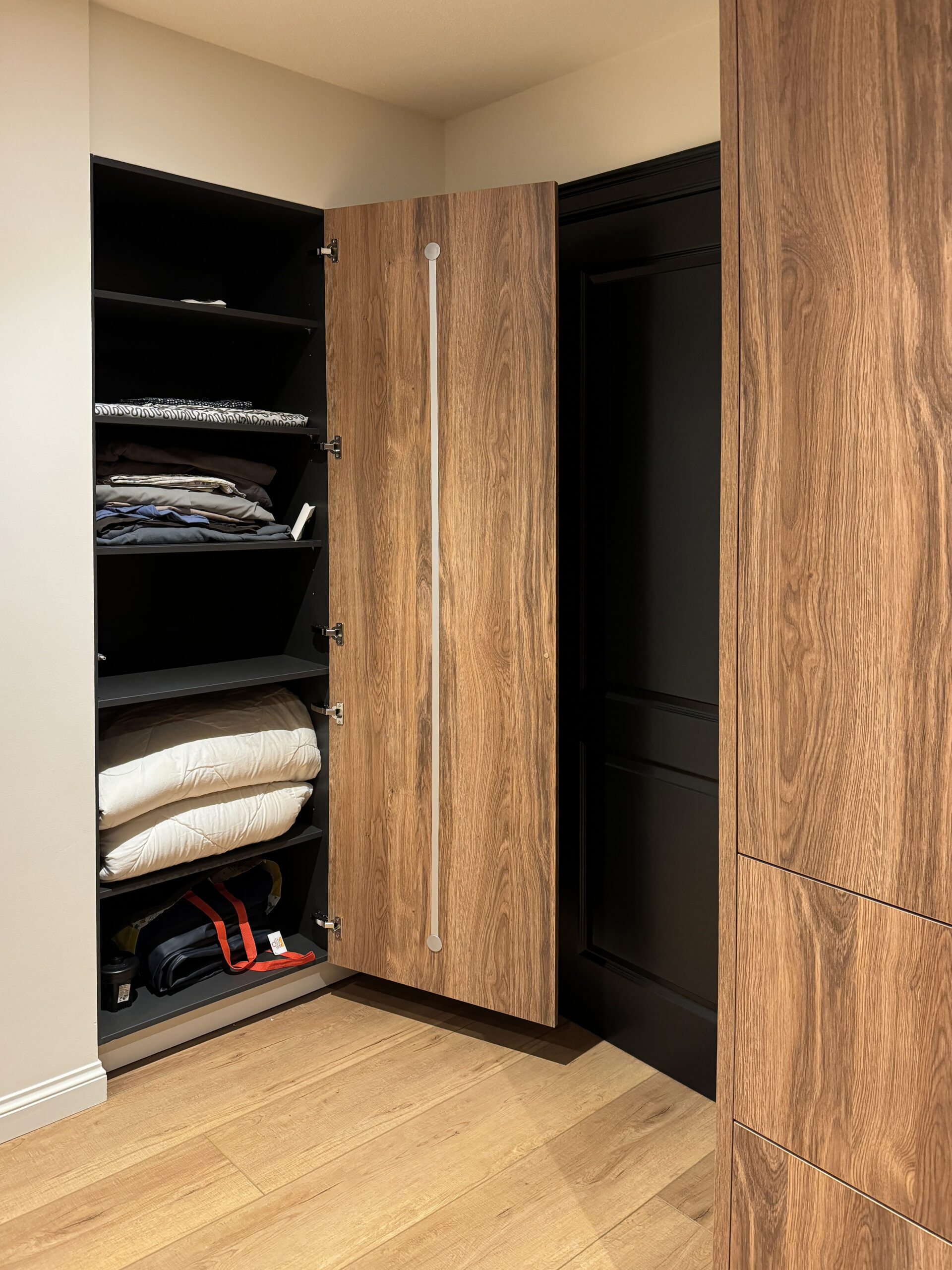 Open maatkast met verstelbare legplanken en antracietkleurig binnenwerk in een dressing op maat