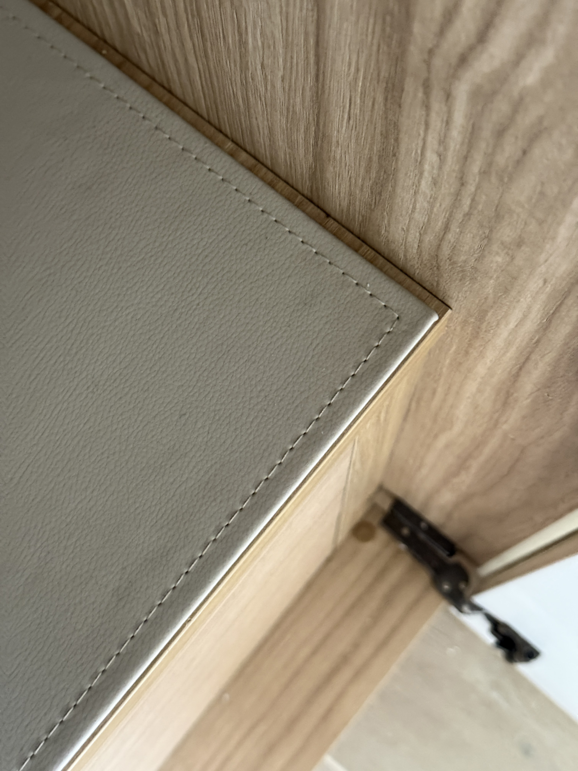 Detail van het gestikte leren bovenblad op de lades in eiken decor