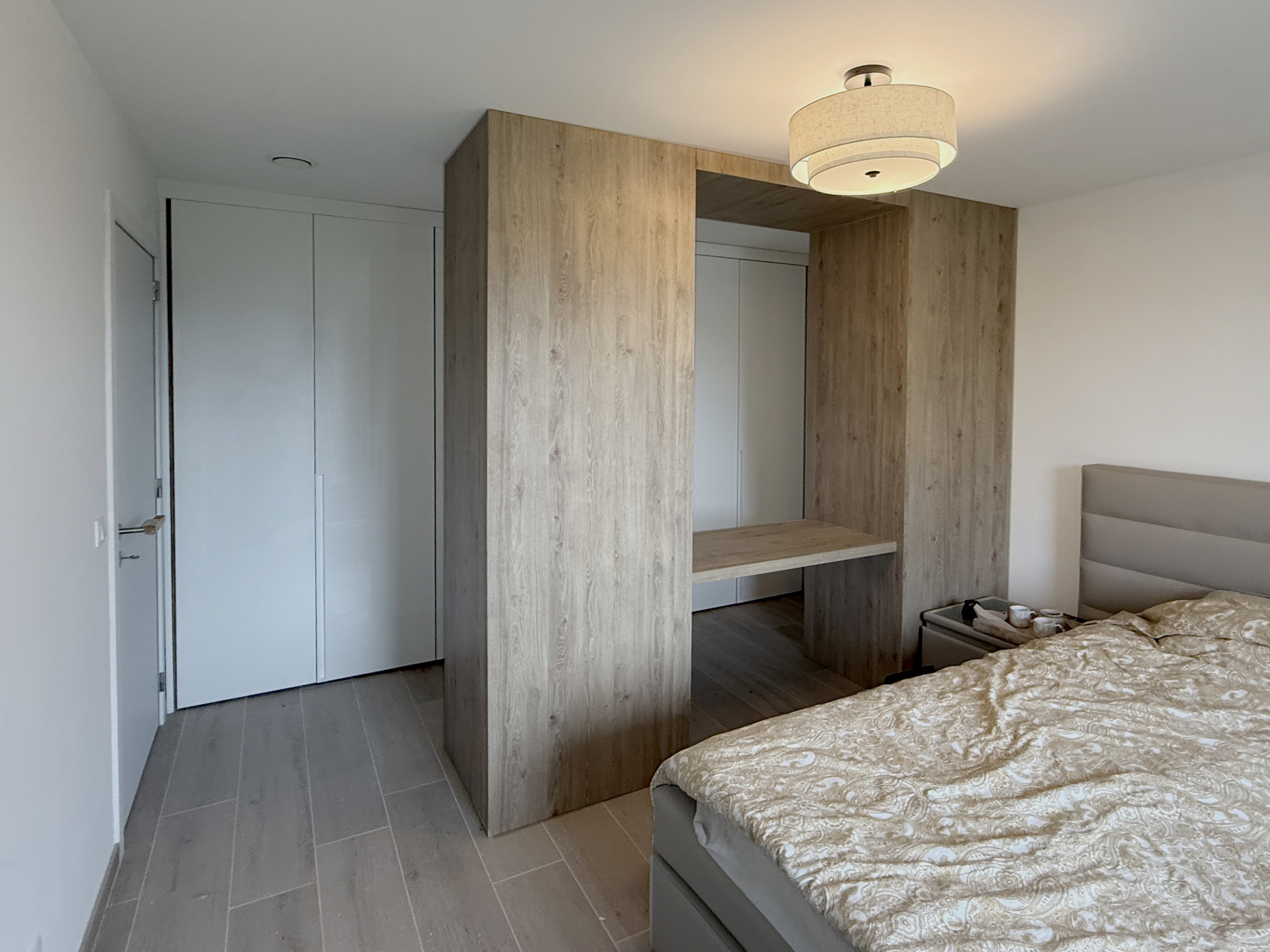 Slaapkamer in Zonhoven met een doorloopdressing in eiken decor achter het bed