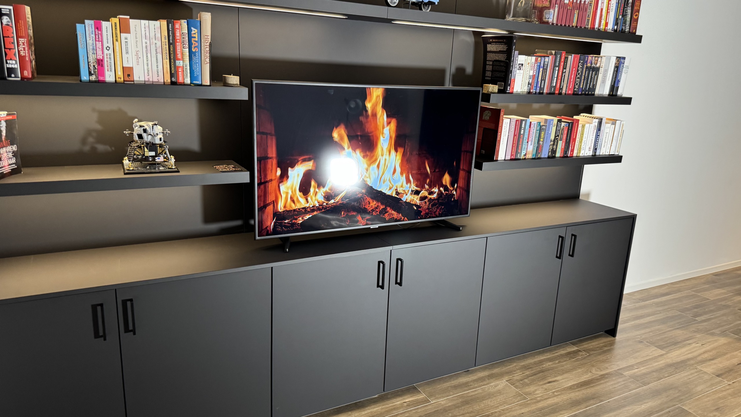 De tv-kast met boekenwand frontaal gezien, met de televisie op het doorlopende blad