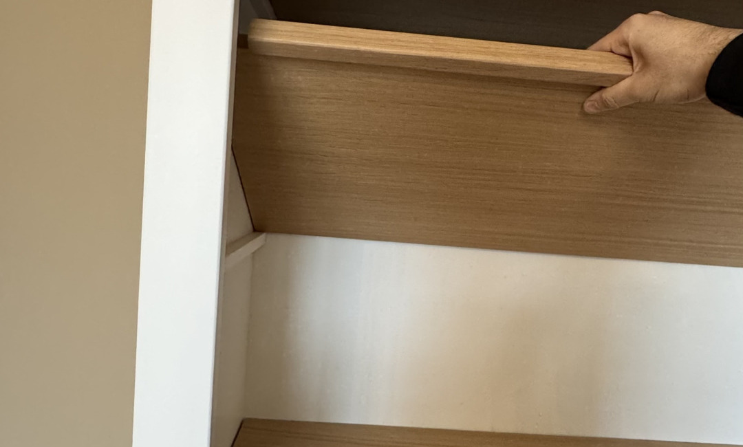 Een hand die een eiken legplank in een kast verzet