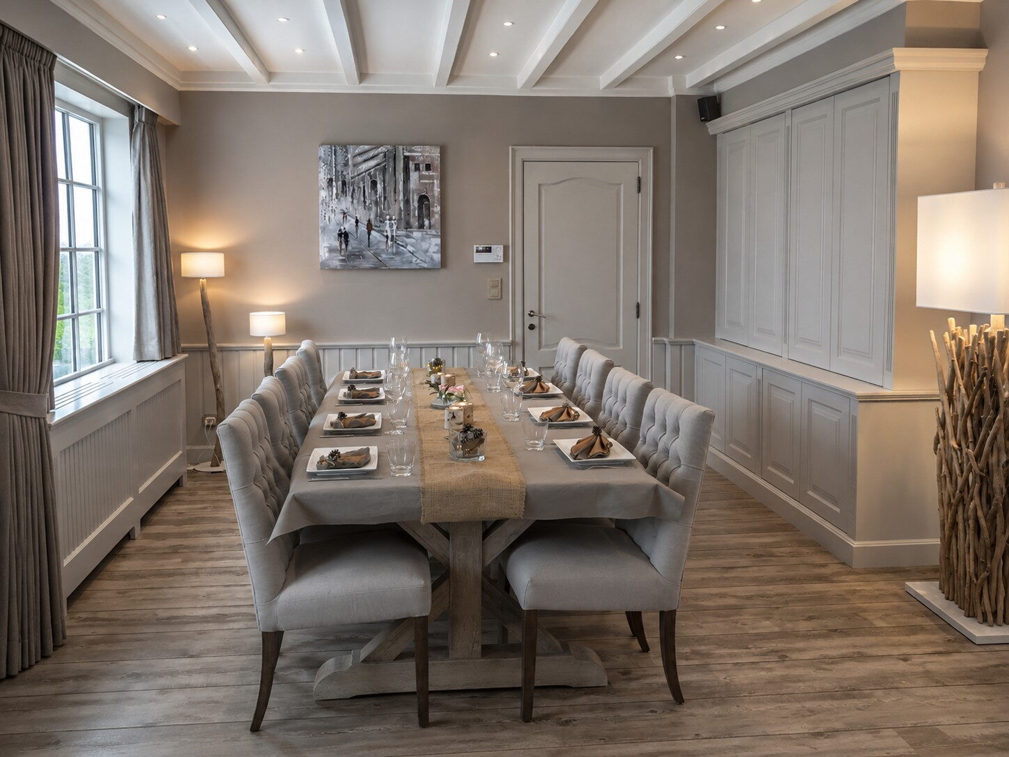 Eetkamer met een lange eiken tafel en gecapitonneerde stoelen tegen een gepaneelde wand