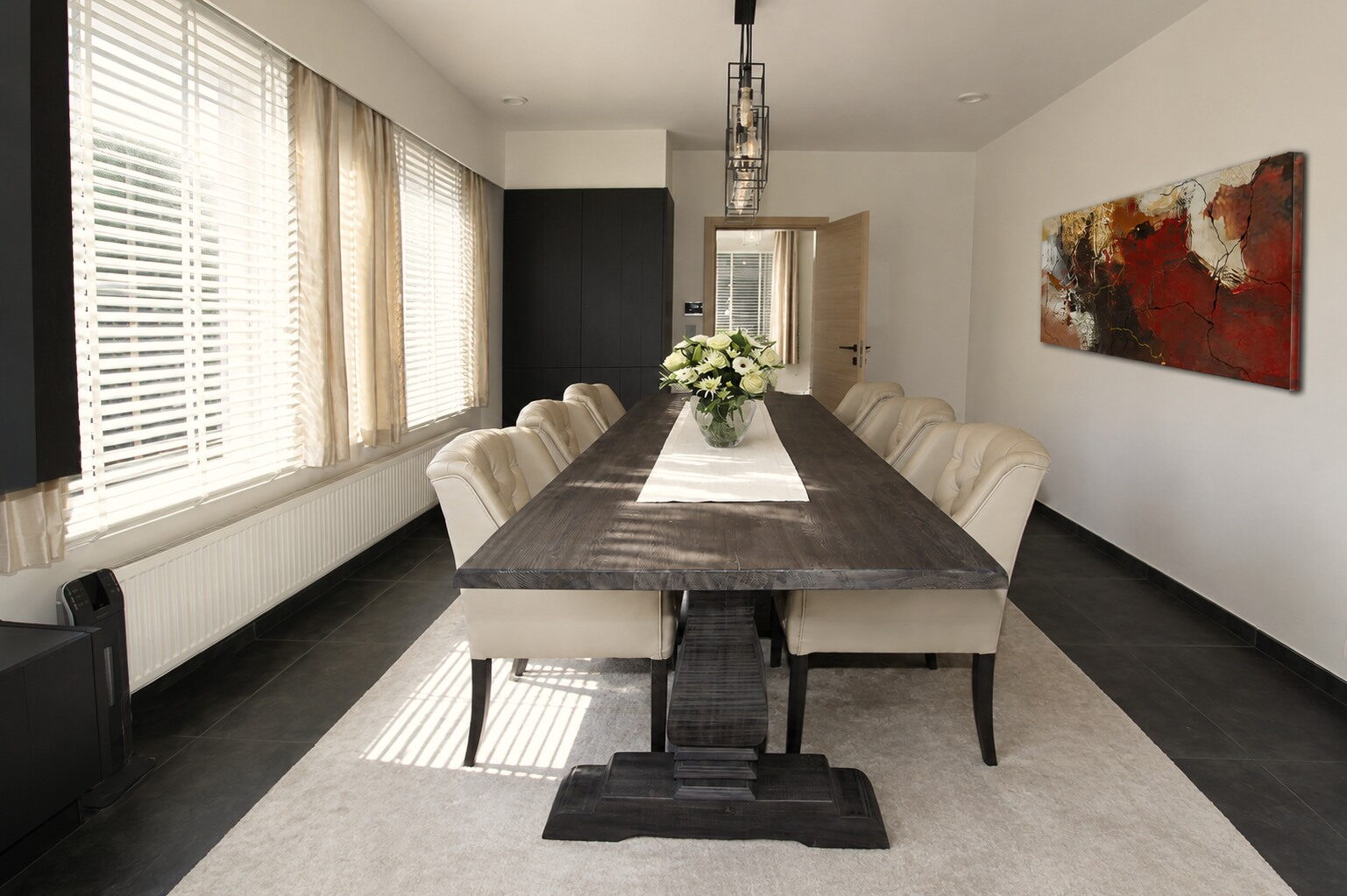 Eetkamer met een lange tafel in donker hout en lichte gecapitonneerde stoelen