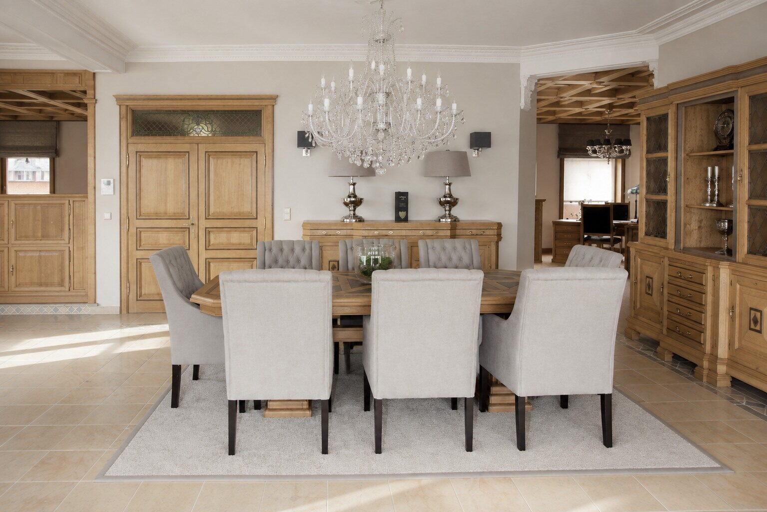 Eetkamer met eiken tafel en witte stoelen naast een vitrinekast in eik