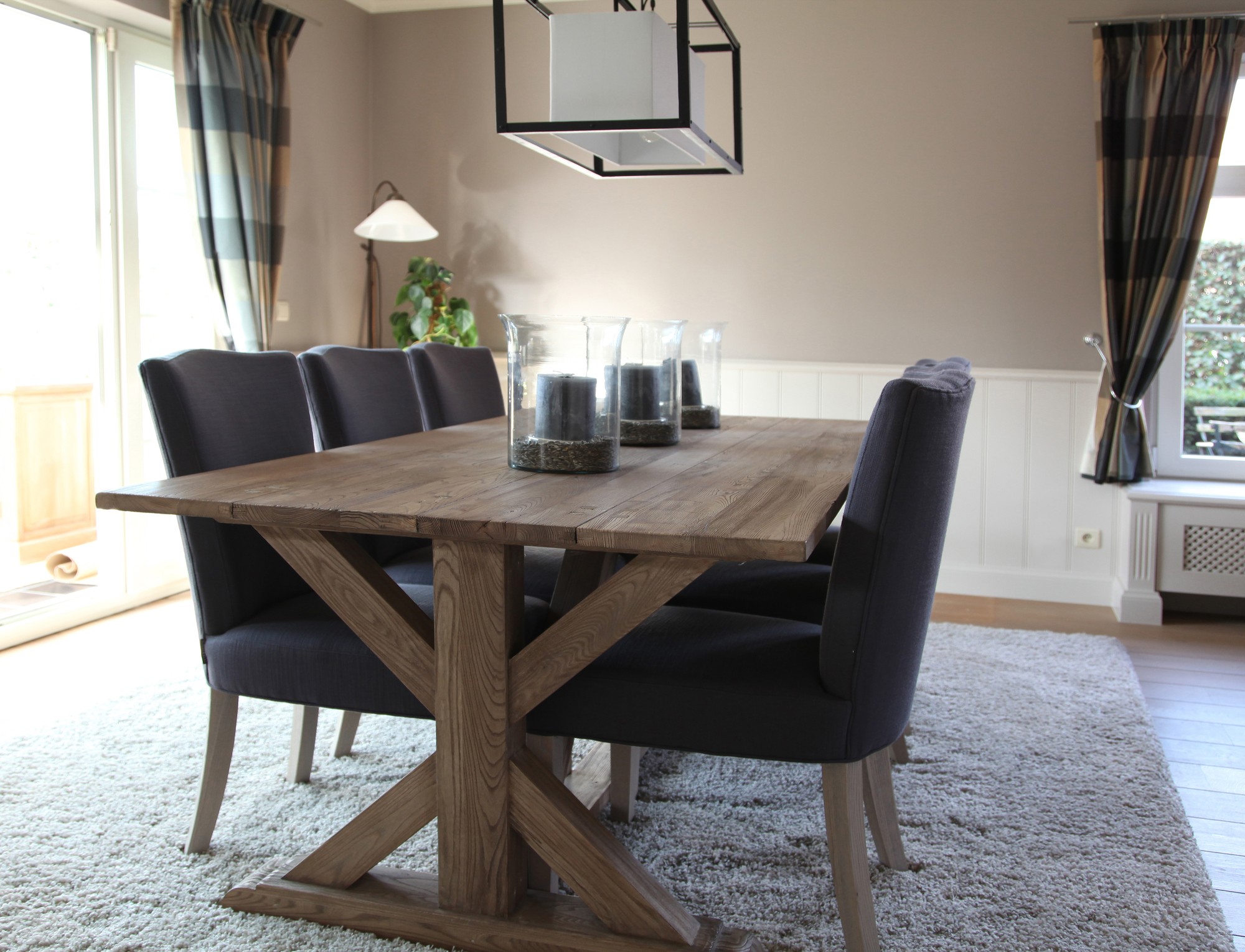 Eiken tafel op kruispoten met donkerblauwe stoelen op een hoogpolig tapijt