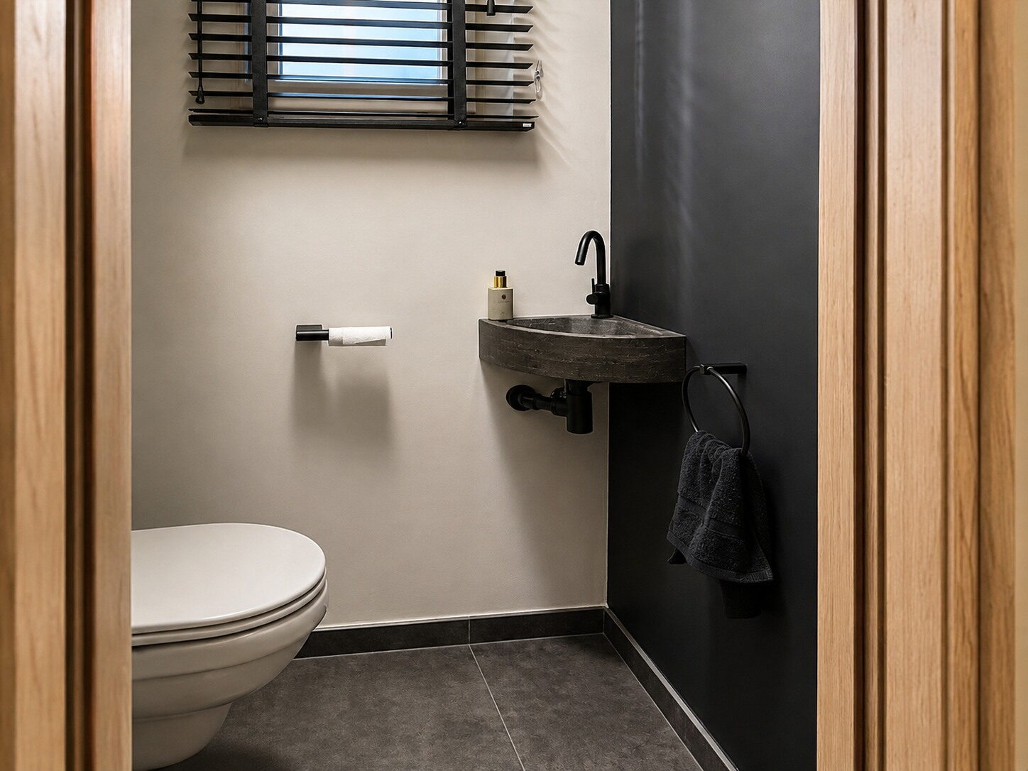 Gastentoilet met een houten omlijsting rond de doorgang en een fonteintje in steen