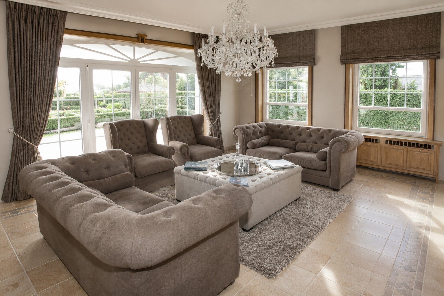 Salon in de erker met chesterfields en zicht op de tuin