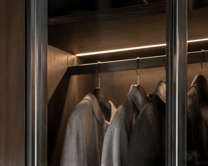 Verlichte hanglat achter glas, met jassen in een kast van notenhout
