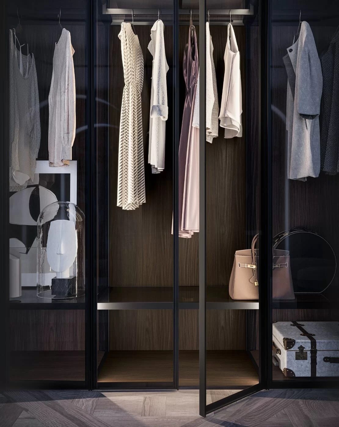 Verlichte kast in donker hout met glazen deuren, hangende kleding, een handtas en een koffer onderaan