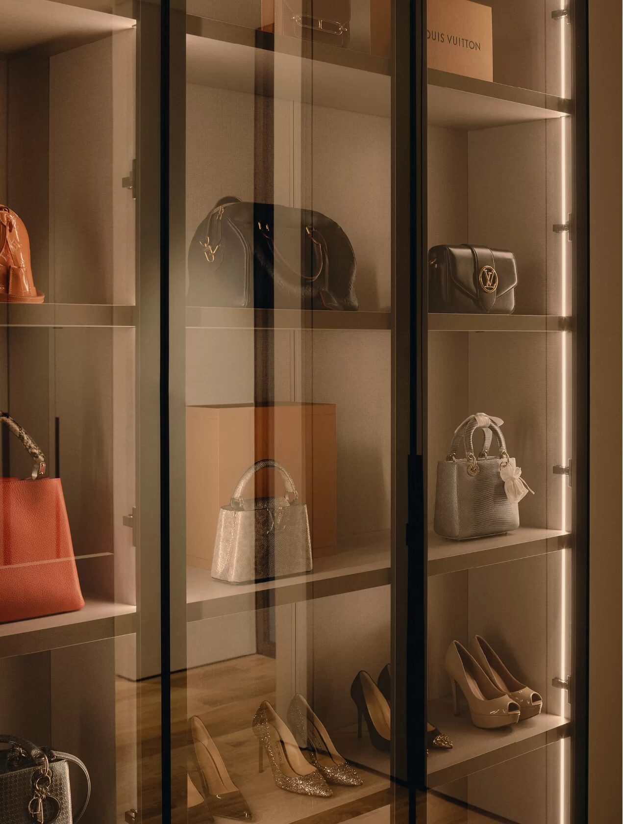 Beleuchtete Vitrine mit Glastüren, Handtaschen und Schuhen auf den Böden