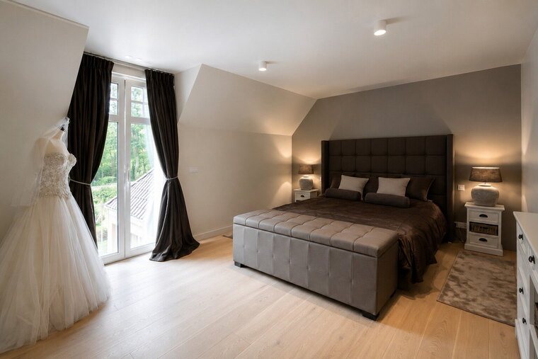 Een bed met een gecapitonneerd hoofdbord dat over de volle breedte van het bed doorloopt.