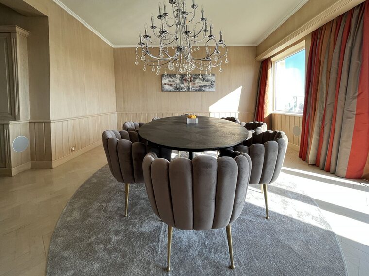 Een ovaal tapijt onder een ovale eettafel met gestoffeerde stoelen, gesneden op de vorm van de tafel.