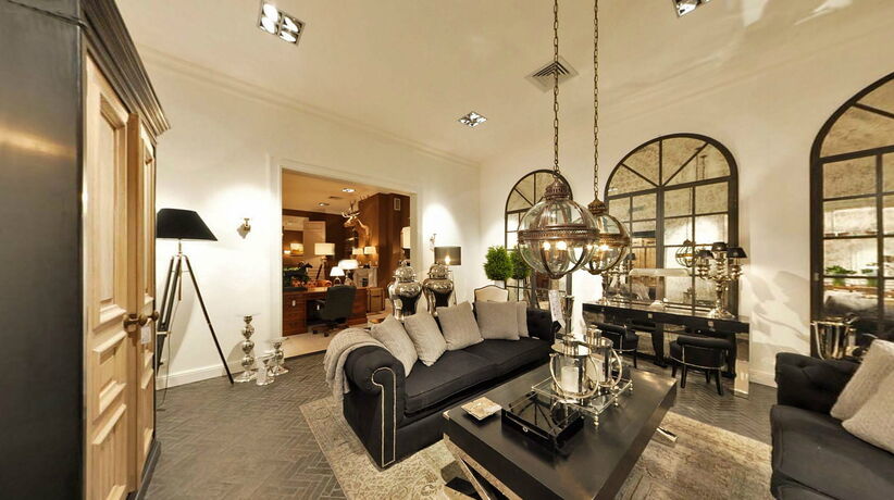 Een hotelsuite met een zithoek, een open doorgang met bogen en maatkasten langs de wand.