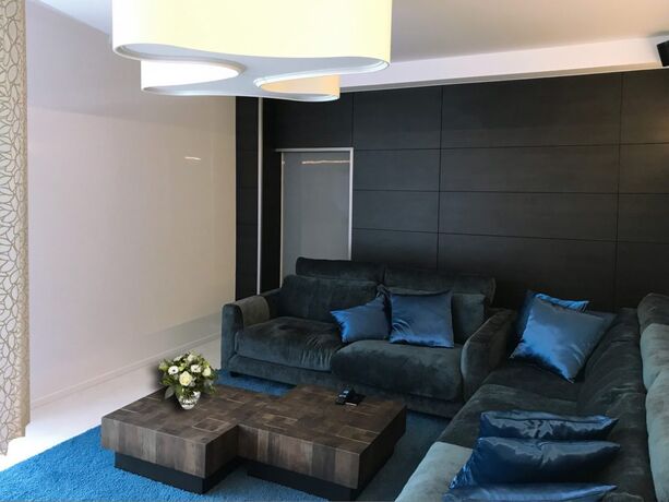Twee salontafels in de vorm van massief houten blokken, los bij te schuiven voor een donkere hoekzetel.