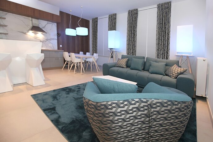 Een petrolblauwe draaifauteuil met een gestructureerde rug, op een blauw tapijt bij een grijze zetel.