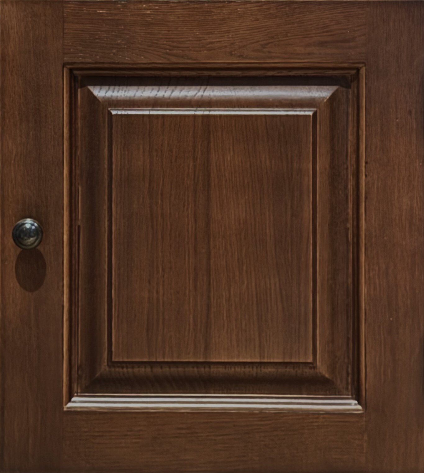 A sample of an oak panelled door in a dark brown stain, with a metal knob.