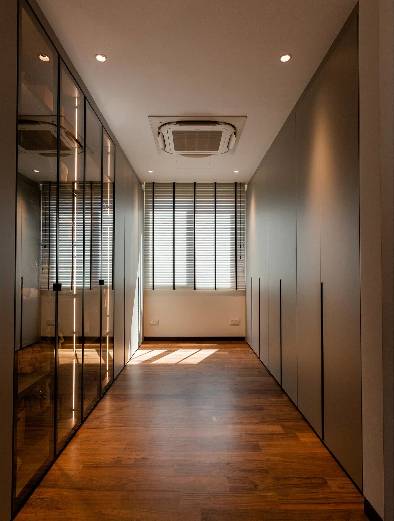 A walk-in wardrobe with glazed doors and lit shelves.