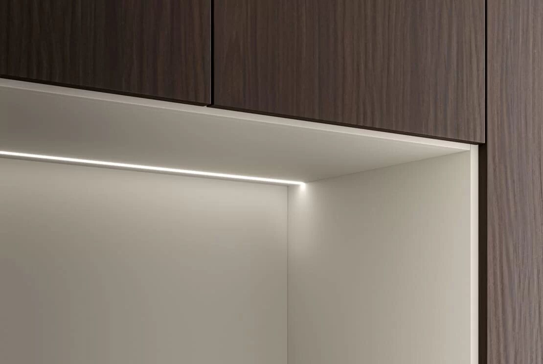 A lit niche beneath a wall unit in dark timber.